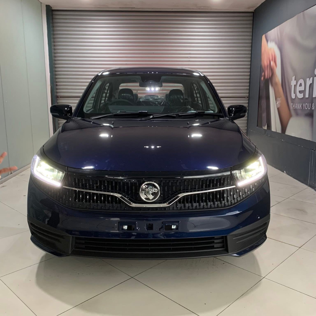 Pandangan hadapan Proton Saga MC3 warna biru gelap dengan lampu hadapan LED menyala di bilik pameran Proton