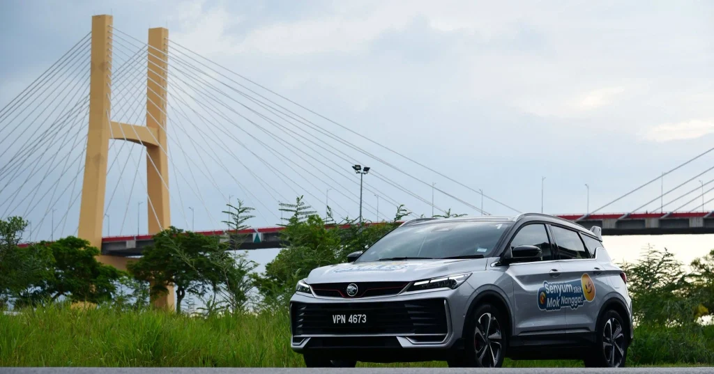 Proton X50 Malaysia berwarna silver di kawasan luar dengan latar jambatan
