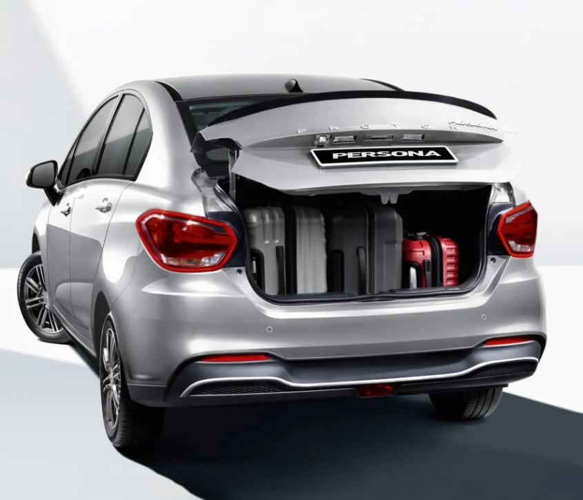 Proton Persona berwarna perak dengan ruang but terbuka yang memuatkan beberapa beg pakaian dan bagasi.